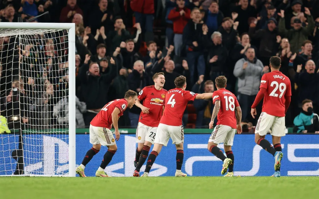 冷门球队庆祝进球，背景为震惊的强队球员